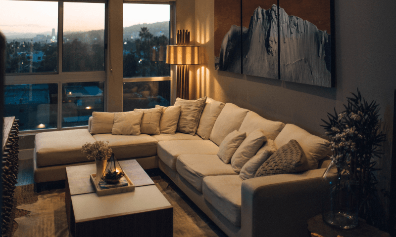 sala com ilumina&ccedil;&atilde;o quente e janela onde se v&ecirc; o p&ocirc;r do sol