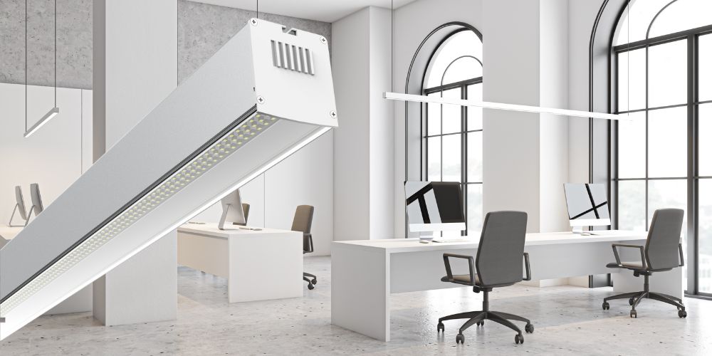 Bureau moderne avec grandes fenêtres et luminaire LED linéaire suspendu en avant.