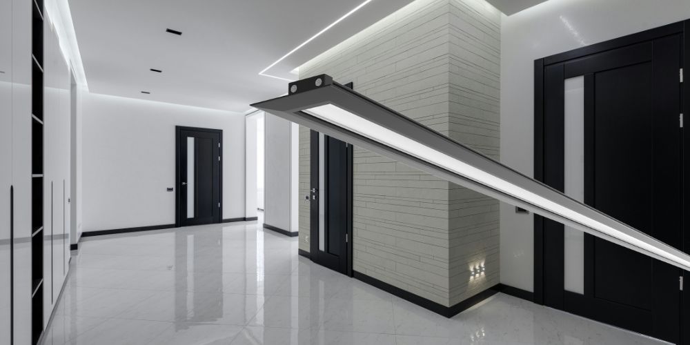 Couloir moderne avec portes noires et éclairage LED encastré, mettant en avant un luminaire LED linéaire.