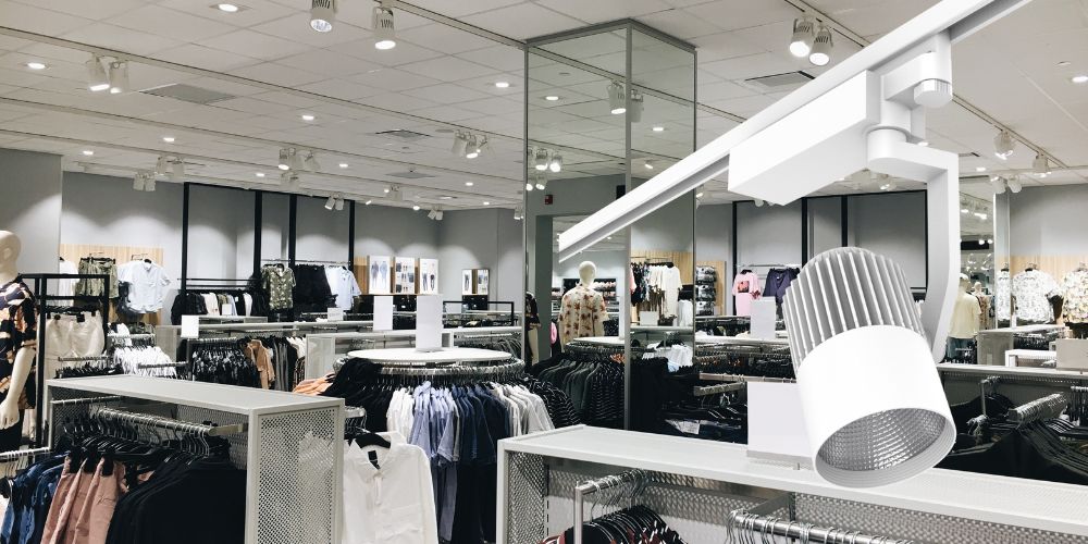Magasin de vêtements avec éclairage LED en panneaux de plafond, mettant en avant un panneau LED carré.