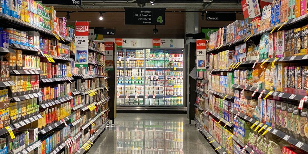 Corredor de supermercado com armário refrigerado iluminado ao fundo